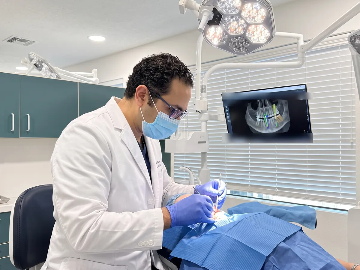 Dr. Walied Eldomiaty, periodontist, placing a single dental implant guided by the 3D CBCT plan on the monitor