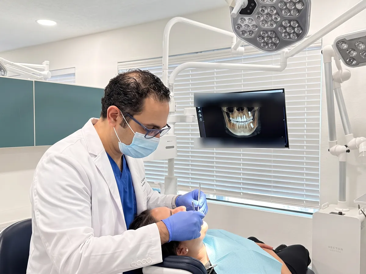 Dr. Walied Eldomiaty examining a patient, with a 3D CBCT scan of the jaw on the monitor