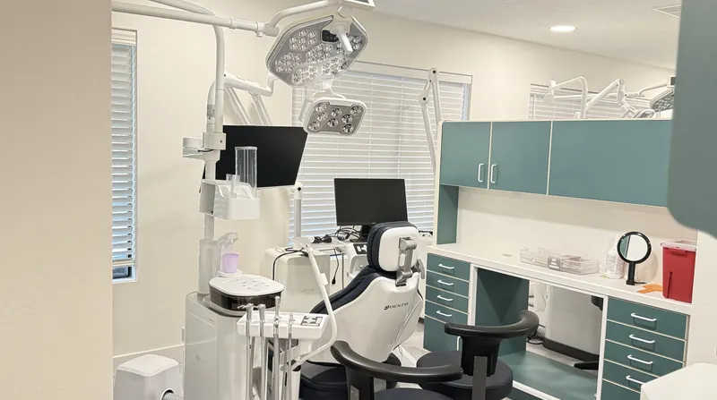 Treatment room at Aloha Dental Specialty Center in Beaverton with a modern dental chair, overhead lights and teal cabinets
